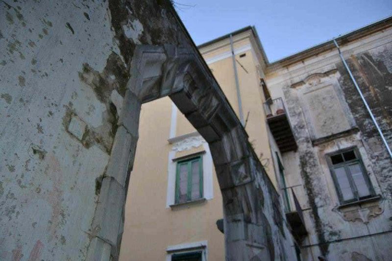 12 Edifici longobardi a Salerno (2026), da Palazzo d'Avossa: stile barocco, coppedè e storia medievale 13 Relitto di un vecchio arco in pietra su un edificio storico abbandonato, con muri consumati e finestre con vetri rotti, scenario di deterioramento e decadenza urbana.