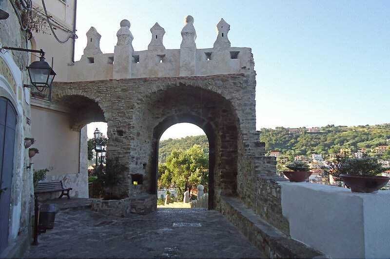 Antico arco in pietra con vista panoramica sulla città e colline verdeggianti, ambiente storico e suggestivo in Italia, perfetto per fotografia e turismo culturale.