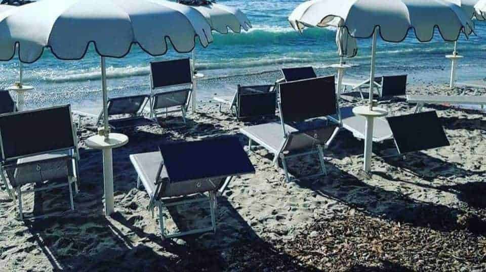 Sdraio da spiaggia e ombrelloni sulla spiaggia di sabbia con vista sul mare, atmosfera rilassante e estiva, ideale per vacanze al mare.