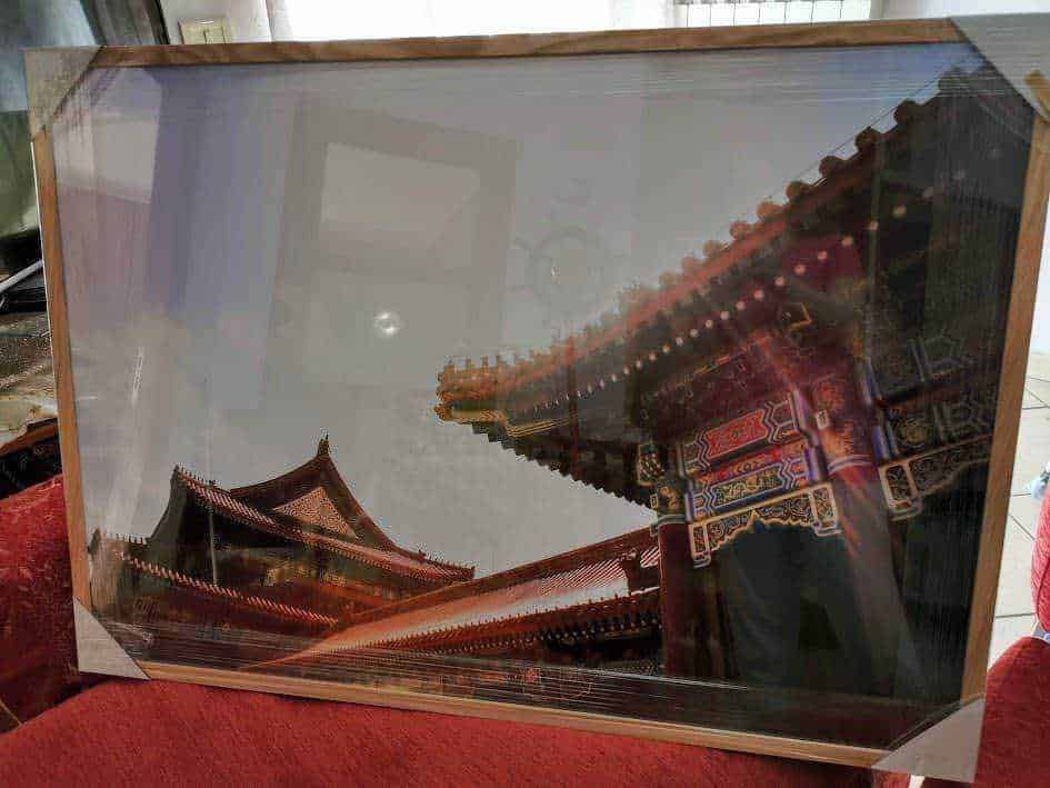 Reflexione di un tempio cinese tradizionale con tetto a pagoda attraverso una cornice di vetro, situato in un ambiente interno, con dettagli artistici e architettonici complessi, ideale per immagini di cultura orientale e architettura.
