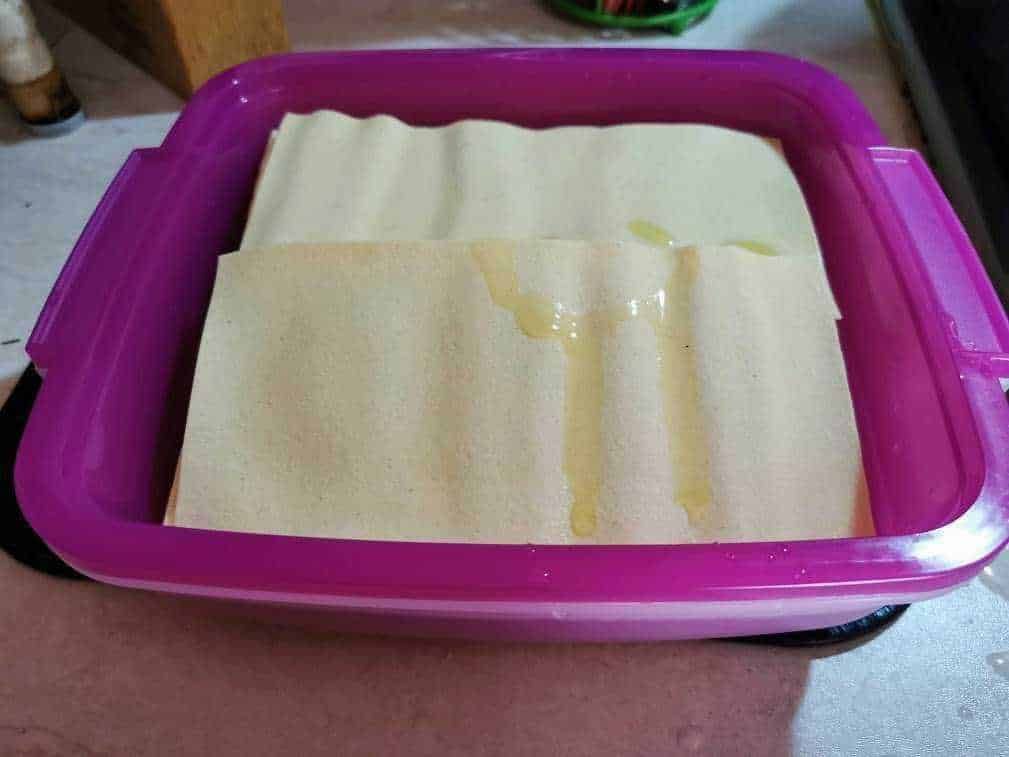 Filone di pasta fresca in fase di asciugatura in contenitore rosa, pronto per essere cucinato o conservato, ideale per ricette di pasta fatta in casa, cucina italiana e tradizionale.