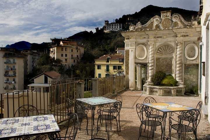 Parchi a Salerno, Duomo e Castello di Arechi (2026): guida completa con orari e prezzi 6 Balcone con vista sulla città e sulle montagne, tavoli all'aperto con sedie in ferro battuto, decorazioni architettoniche eleganti su un edificio storico in Italia.