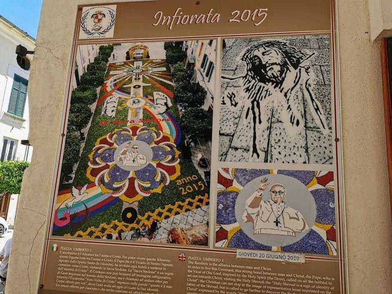 Sant'Agata de' Goti chiese ed eventi della Perla del Sannio 18 Il-ALT: Dettaglio dettagliato di una decorazione floreale di grandezza naturale con tema religioso, realizzata nel centro di una città italiana, con colori vivaci e simboli religiosi.