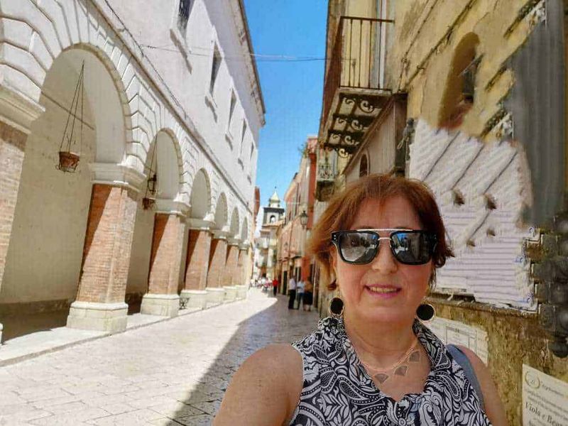Sant'Agata de' Goti chiese ed eventi della Perla del Sannio 13 Scorcio di strada storica con arconi in mattoni e donna con occhiali da sole che prende un selfie a lume di sole.