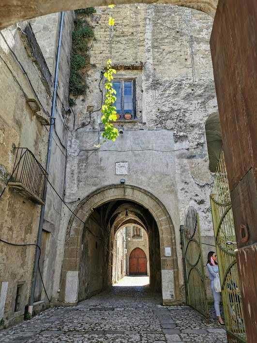 Vecchia via con arco in pietra e architettura medievale, dettaglio di porta e casa storica, scena suggestiva di un quartiere storico italiano, ambienti di epoca antica.