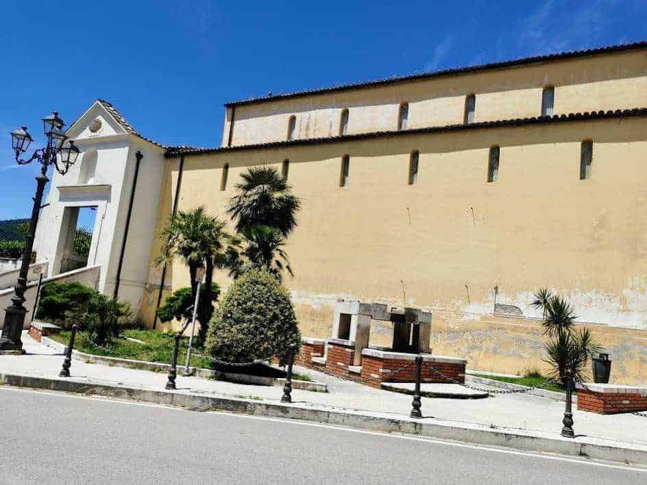 Fascino storico, con mura antiche e palme tropicali, in un'architettura tipica italiana. Ambientazione suggestiva di un borgo mediterraneo a cielo sereno. Perfetta per appunti e reportage sui luoghi di cultura e turismo.