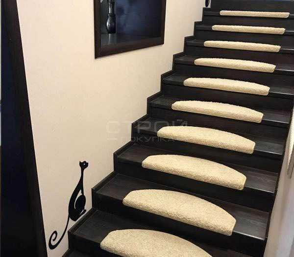 Fondo nero con stuoie beige ovali sui gradini di una scala moderna. Elemento decorativo di stile elegante e funzionale, ideale per chi cerca soluzioni di arredamento innovative e di design.