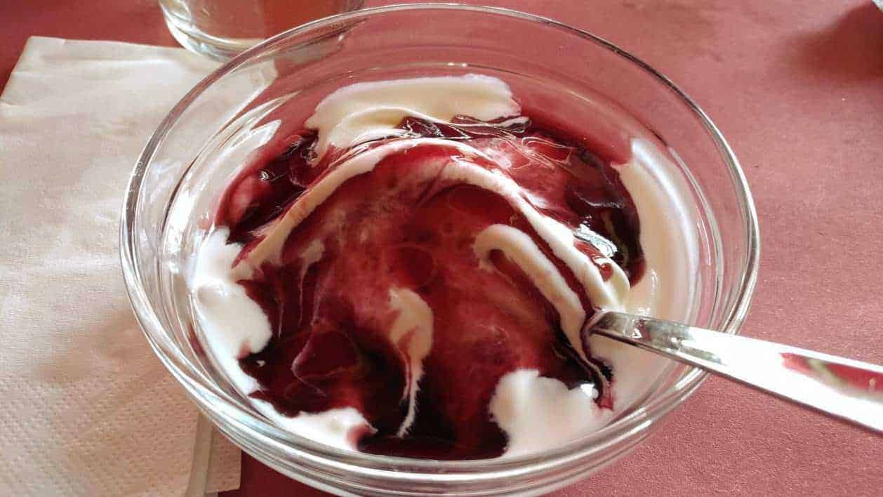 Crema di yogurt e frutti di bosco in una ciotola trasparente, perfetta per dessert estivi genuini e salutari.