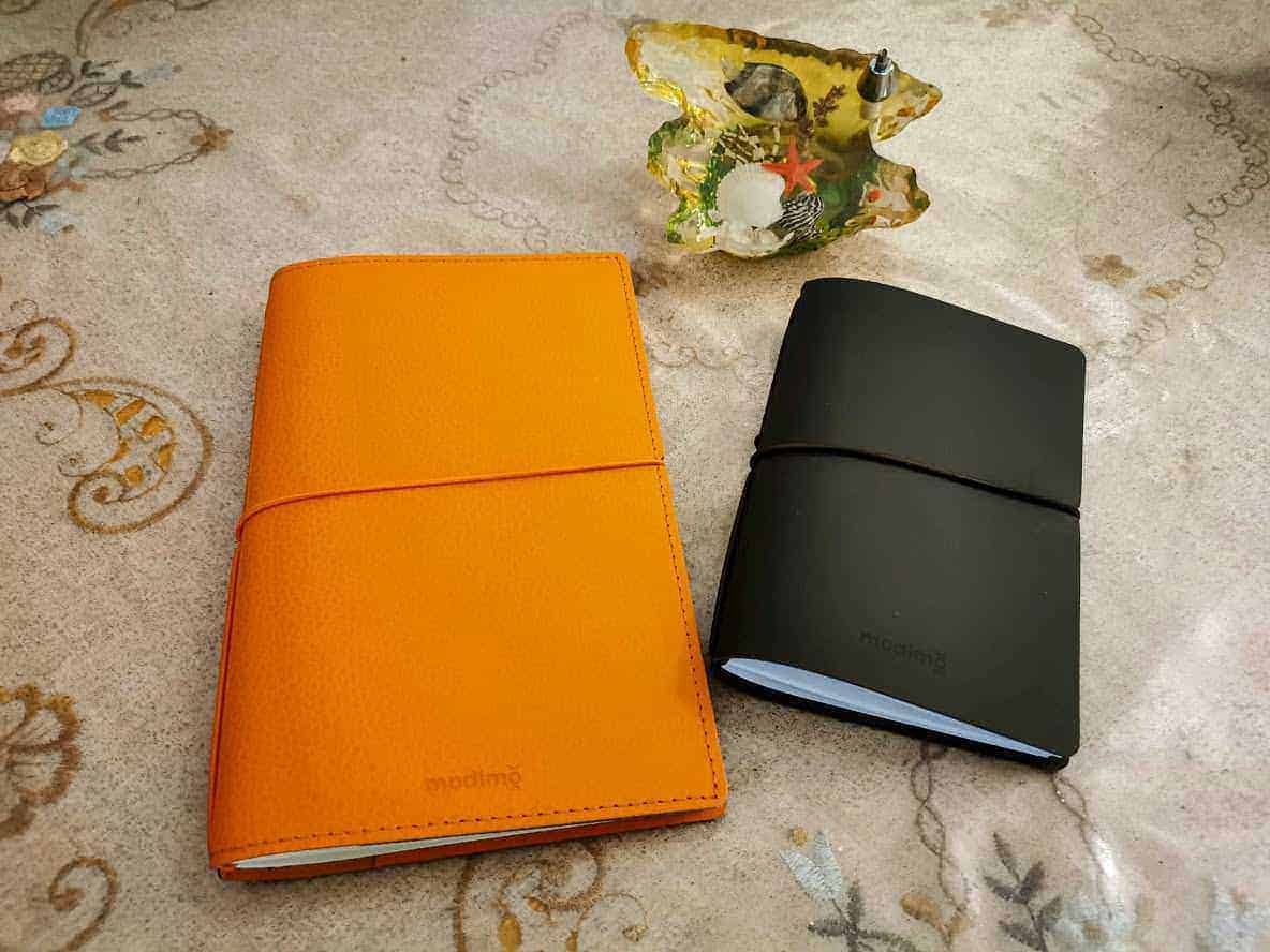 Highlighted notebooks and decorative shell on elegant tablecloth.