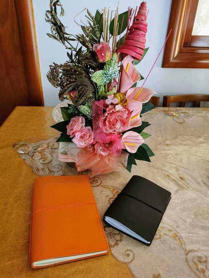 Bellissimo bouquet di fiori con rose e calla rosa, decorato con foglie e dettagli naturali, su tavolo in legno per occasioni speciali o decorazioni eleganti.