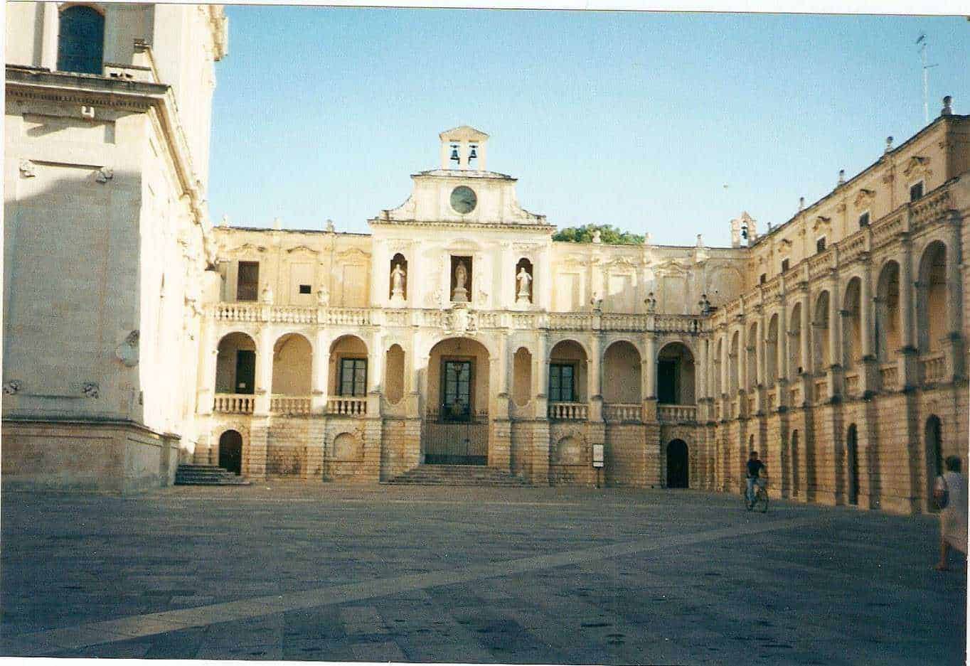 Palazzo storico con archi e statue, centro urbano, architettura barocca, edificio storico in pietra, piazza antistante, patrimonio culturale italiano, atmosfera mediterranea, viaggio in Italia, luogo di interesse storico.