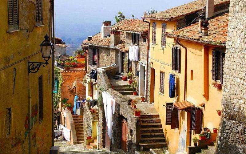 Colorful hillside houses with laundry hanging outside, narrow stairways, and charming windows in an Italian village. A picturesque scene showcasing Mediterranean architecture and vibrant local life.
