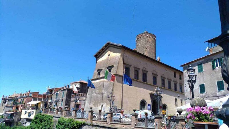 13 città da vedere vicino Roma nel Lazio meridionale 20 Ville storiche italiane con bandiere e architettura tipica, sotto un cielo azzurro.