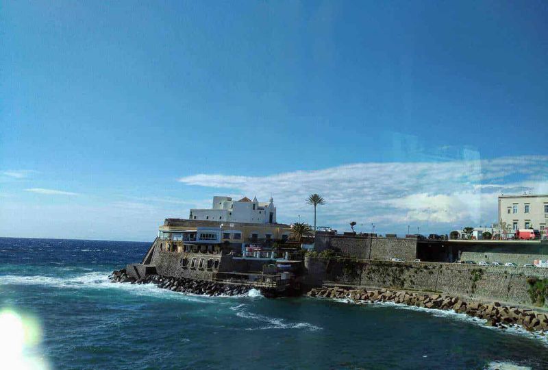 6 Comuni isola Ischia, cosa fare in 3 giorni 9 Spiaggia di Sliema con vista sul mare e edifici storici, cielo azzurro e onde che si infrangono sulla costa.
