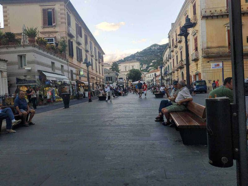Il paesaggio urbano, quali problemi in città? 4 Vivace strada pedonale nel centro storico di Sorrento con negozi, bar e persone che si rilassano, circondata da edificio storici e affascinanti vicoli, con vista sulle colline circostanti.
