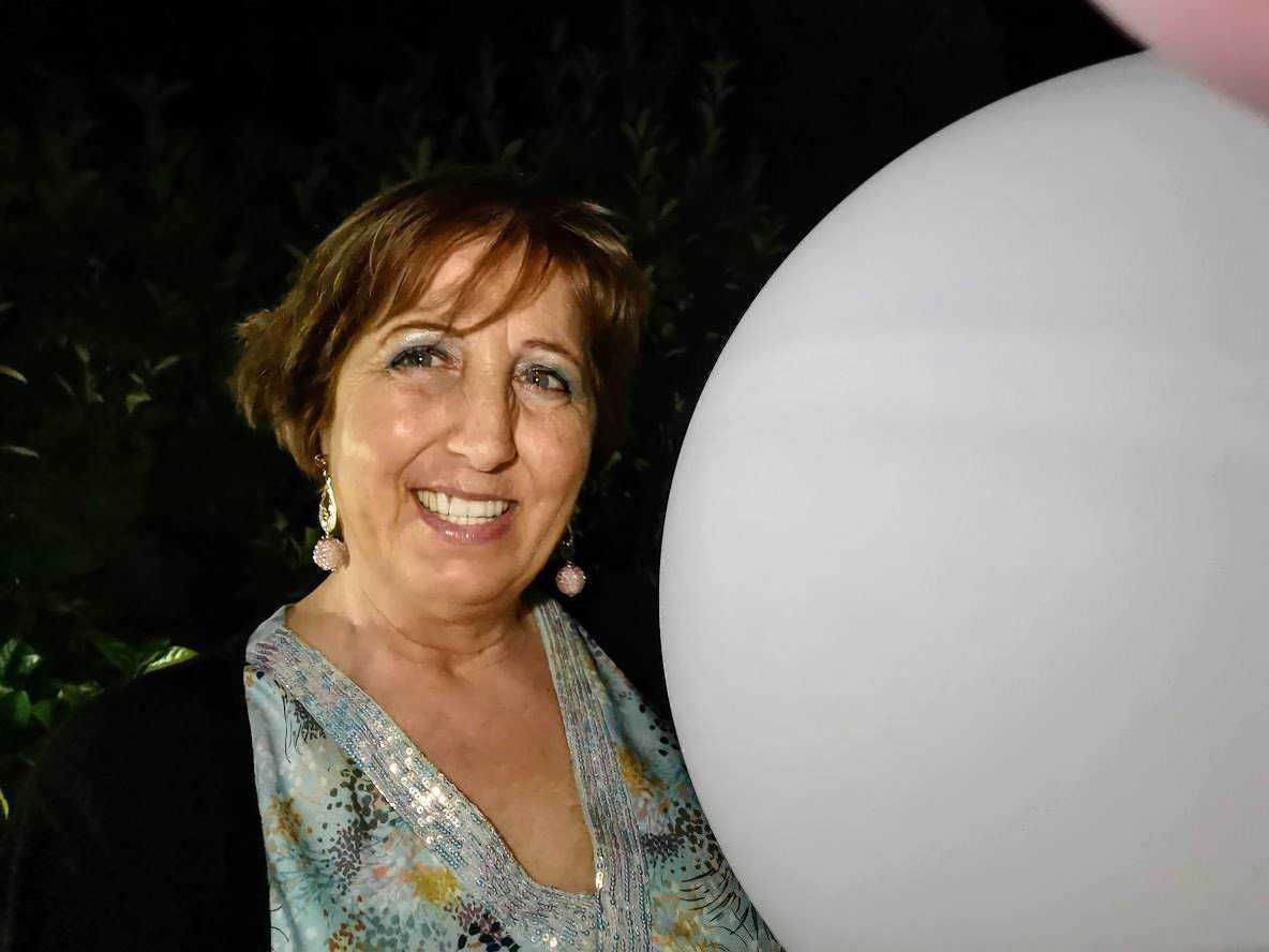 Donna sorridente con palloncino bianco in festa, abbigliamento elegante e accessori di gioielleria, atmosfera festosa, evento speciale, sorrisi e allegria, immagini di celebrazione.