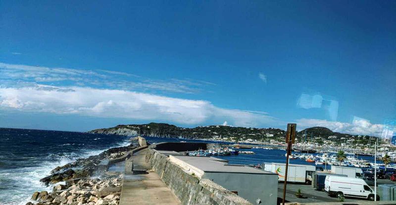 3 isole Flegree: Ischia, Procida e Capri tra mare, terme e borghi 6 Vela e scogli in mare, panoramica Ischia Porto con barche e yacht, isole e onde.