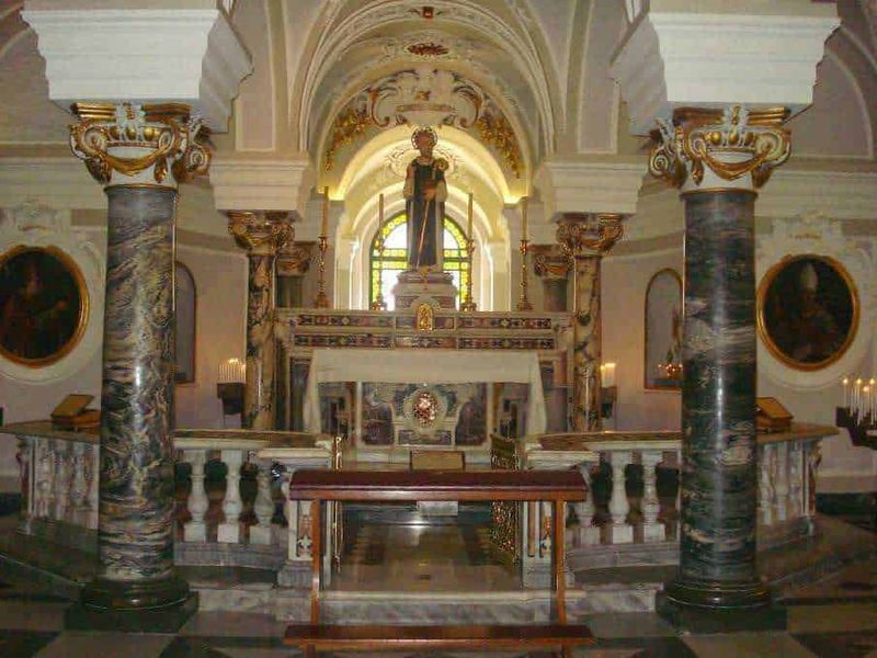 6 Edifici religiosi a Sorrento. Quali sono? 6 Scultura sacra in chiesa barocca, decorazioni dorate e colonne in marmo, ambiente di culto con atmosfere storiche e spirituali per appassionati di arte religiosa.