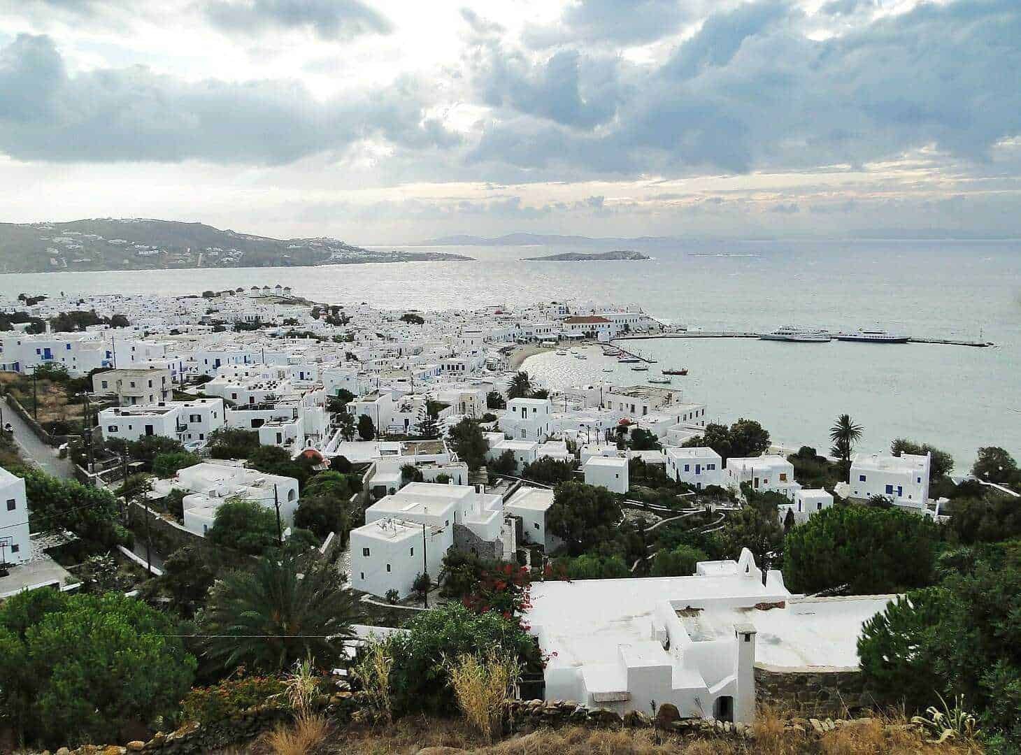 Pointer osteria di Mykonos, Grecia, vista panoramica delle case bianche, edificio in stile tradizionale, mare cristallino, cielo nuvoloso, attività turistica, località costiera.