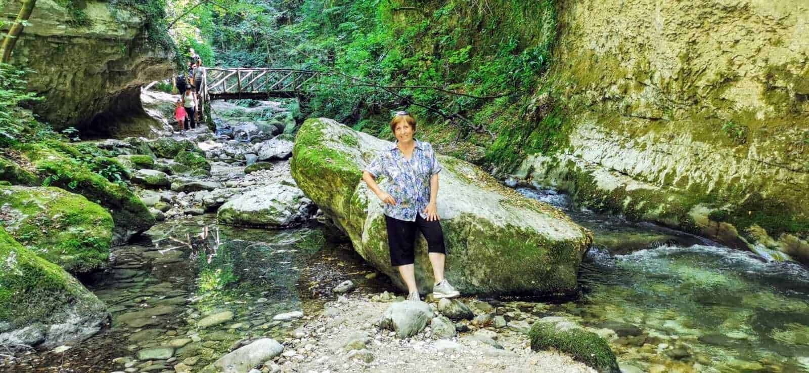 Lunga passeggiata nel parco naturale con paesaggi di fiume, rocce verdi e vegetazione rigogliosa, ideale per escursioni e relax nella natura.