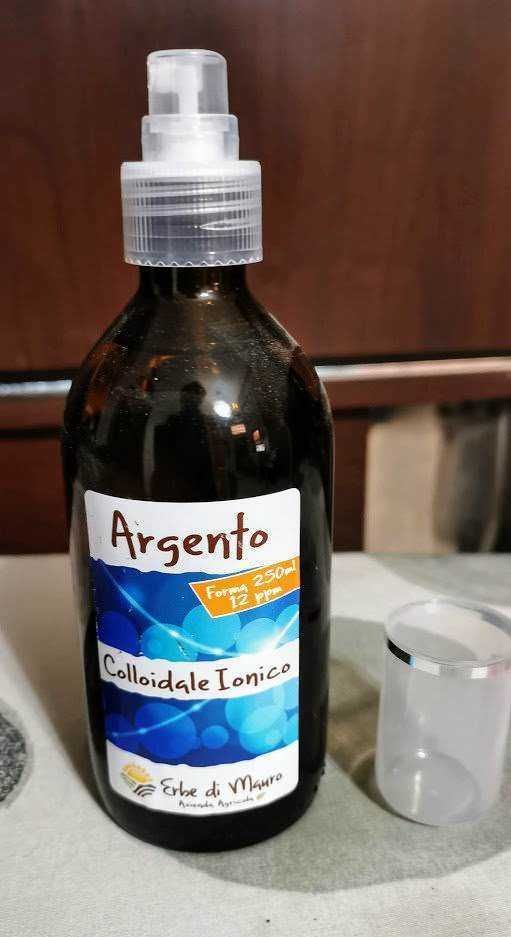 Flacone di Argento Colloidale Inciato con spray per uso domestico e cosmetico, con tappo trasparente, etichetta blu con bolle e scritte nere, contenitore da laboratorio o per trattamento naturale.