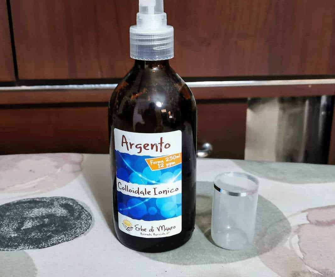 Profumo di argento, composto colloidale ionico in bottiglia con spruzzatore, prodotto naturale e curativo, ideale per salute e benessere, presentato su tavolo in ambiente domestico.