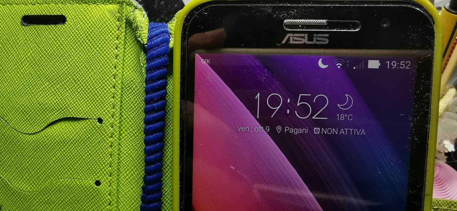 Smartphone ASUS con custodia gialla e accessori blu, schermo acceso con orario 19:52, mostra notifiche di rete e temperatura, ideale per articoli su tecnologia e gadget.