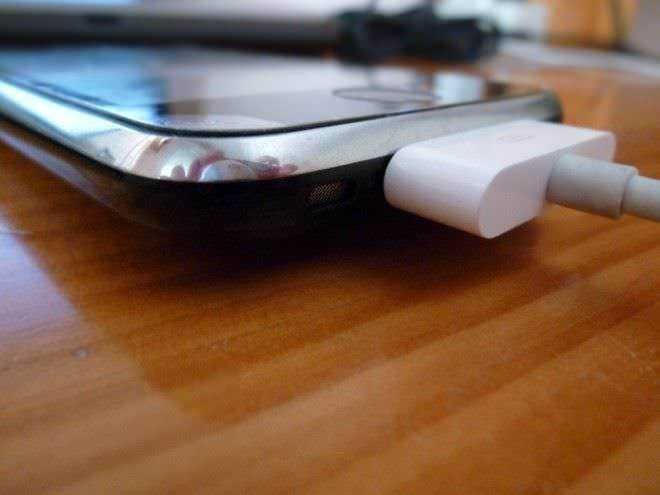 Caricatore di smartphone collegato a un dispositivo mobile su superficie di legno.