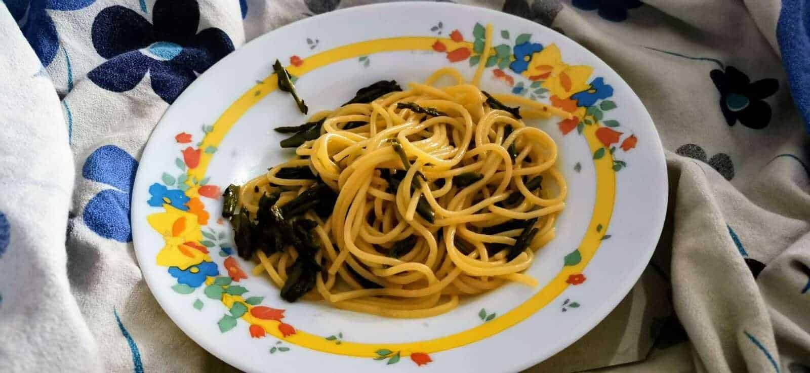 Spaghetti al vongole con nero di seppia in un piatto decorato, pasta italiana, ricetta di mare, cucina mediterranea, piatto di pasta elegantemente presentato.