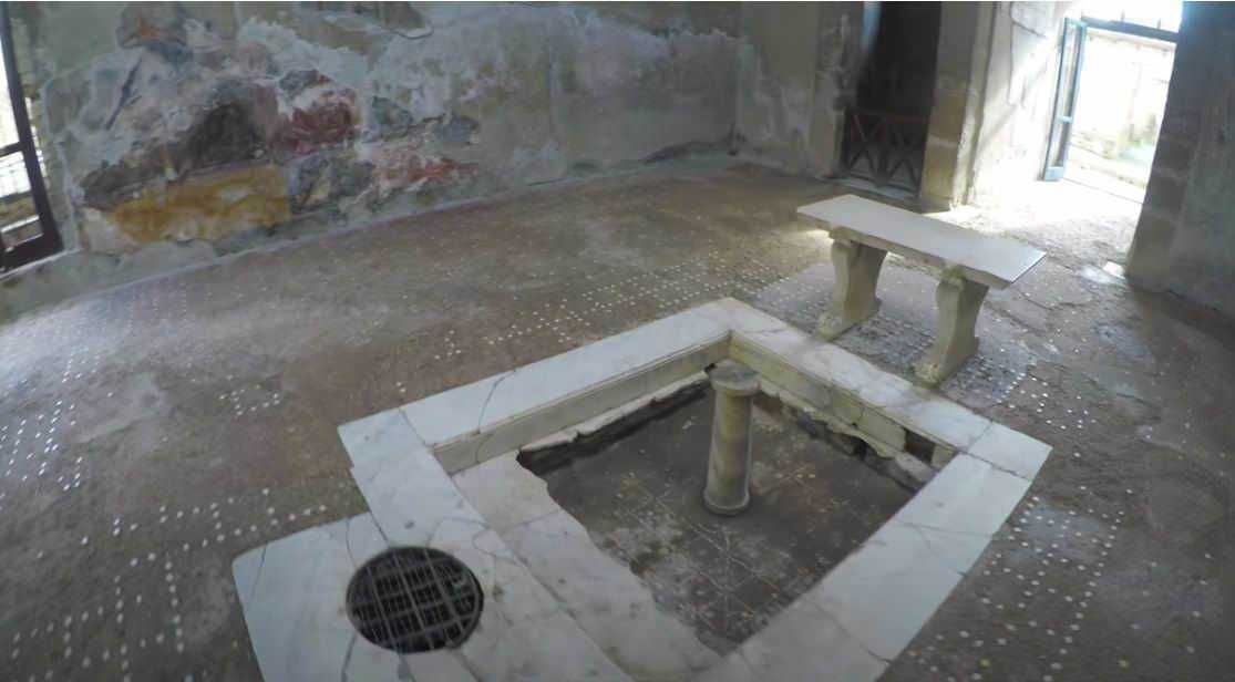 Antico pozzo in pietra all'interno di una stanza storica con pareti di pietra e pavimento in pietra, restaurato come elemento decorativo o funzionale in un edificio storico.