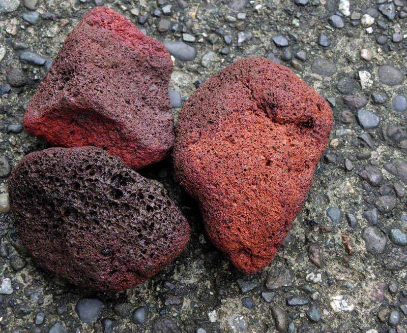 Pietra pomice piedi. Quale scegliere tra naturale e sintetica? 2 Pietra pomice per i piedi: Pietra pomice piedi. Quale scegliere tra naturale e sintetica? pietre laviche rosse e nere sulla strada gravellata.