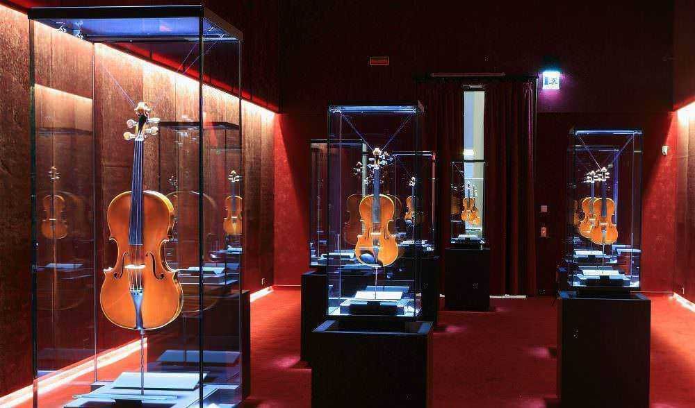 Viaggio tra violini storici in una mostra in una sala espositiva elegante e suggestiva, illuminata con luci moderne, ideali per gli appassionati di strumenti musicali classici e collezionisti d'arte.