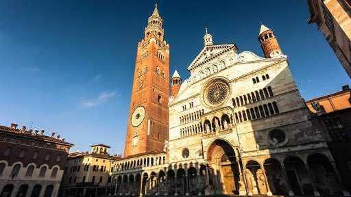 Campanile e facciata del Duomo di Pisa, iconica architettura romanica, patrimonio UNESCO, simbolo culturale e turistico del capoluogo toscano, vicino al fiume Arno, con cielo azzurro sullo sfondo.