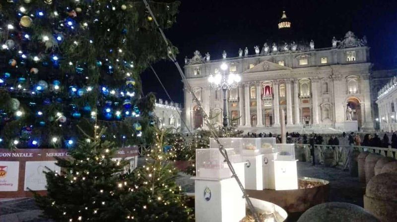 Natale posti da visitare in Italia da Nord a Sud 2 Natale in italia da nord a sud: Colorate installazioni di luci natalizie sul cielo stellato, decorazioni luminose di pesci e figure di animali sulla piazza di un centro storico, creando un'atmosfera festosa e magica.