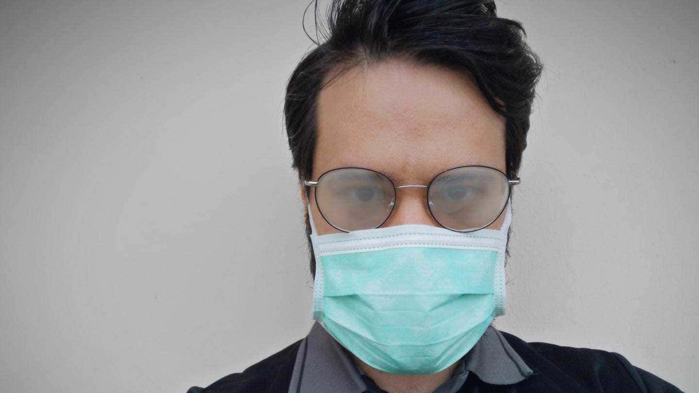 Mascherina protettiva, uomo con occhiali e mascherina blu, sicurezza sanitaria, prevenzione COVID-19, salute pubblica, fronte bianca semplice, immagine di sensibilizzazione, appunti sul blog, informazione sulla pandemia, aggiornamenti sanitari, stile di vita responsabile.