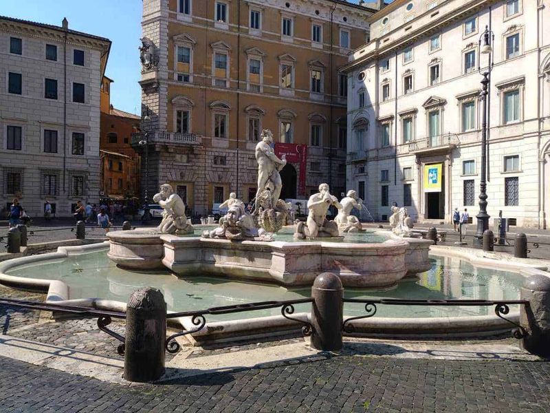 Piazza Navona a Roma in stile barocco 6 Fontana storica con sculture in pietra situata in una piazza di Roma, circondata da edifici storici e architettura classica, ideale per foto turistiche e passeggiate urbane.