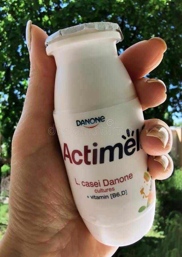 Yogurt e diabete: Yogurt Actimel Danone in bottiglia, vista in mano con sfondo natura verde e foglie.