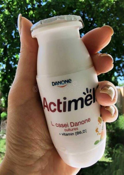 Yogurt quando mangiarlo. Prima o dopo i pasti per i diabetici? 2 Yogurt e diabete: Yogurt Actimel Danone in bottiglia, vista in mano con sfondo natura verde e foglie.