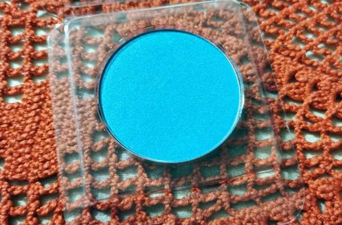 4 regole trucco antietà con BB, ombretto e matita per sopracciglia 6 Blue eyeshadow in a round container on a textured orange background.