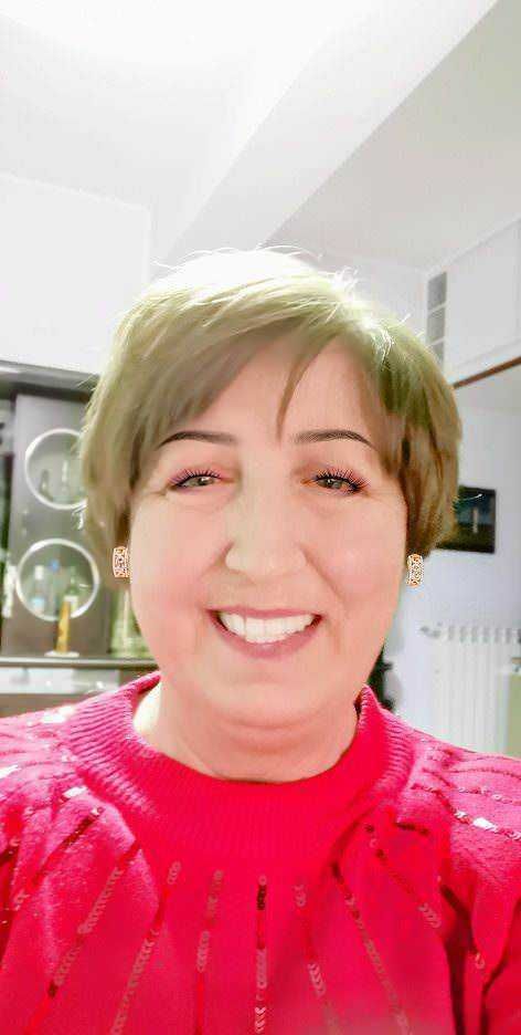 S mascarada sorridente donna con short hair, indossa un maglione rosso con dettagli glitter, sfondo di ambiente domestico moderno.