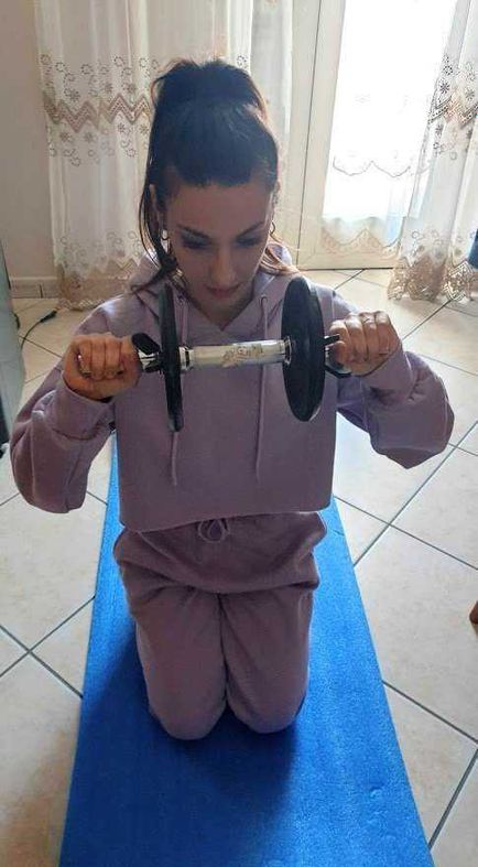 Come vestirsi bene con outfit sportivo ma elegante 4 Scolara adolescente che fa esercizi di fitness con manubri su tappetino yoga in casa.