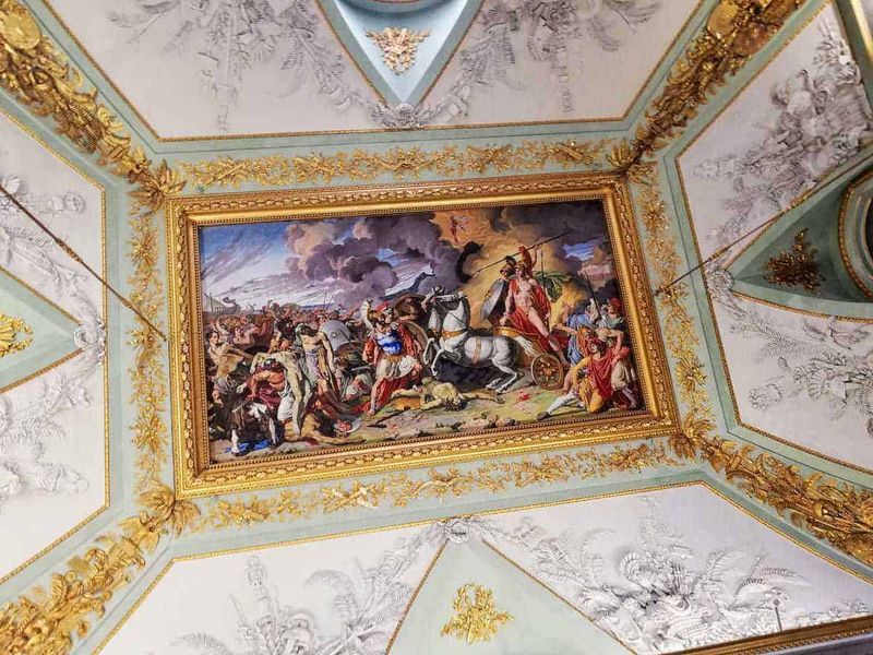 Cosa vedere Reggia di Caserta, location Star Wars 7 Dipinto storico che rappresenta una battaglia epica, incorniciato da un soffitto decorato con dettagli dorati e ornamentali, situato in un palazzo o museo artistico di prestigio.