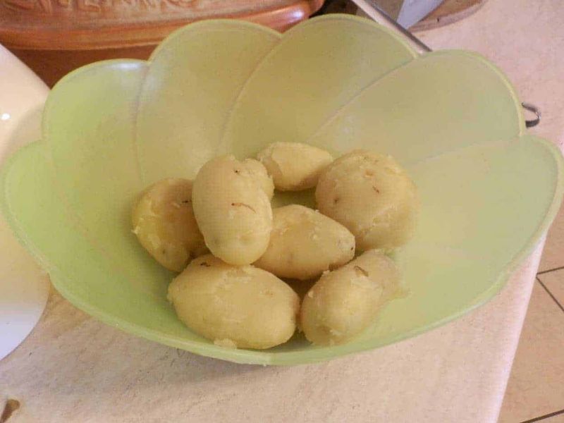 Purè di patate istantaneo, origine del tubero 2 Pomodorini di patate novelle in ciotola verde, pronti per essere cotti o utilizzati in ricette rustiche e genuine, ideale per piatti tradizionali italiani.