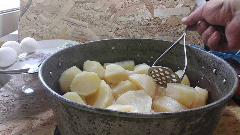 Purè di patate senza latte per vegetariani 3 Uova sode e patate lessate in una pentola, preparazione di un piatto tradizionale italiano.