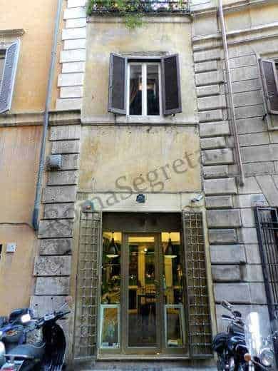 Entrata di un edificio storico con porta in vetro e finestre in stile classico, situato in un quartiere urbano di Roma, Italia.