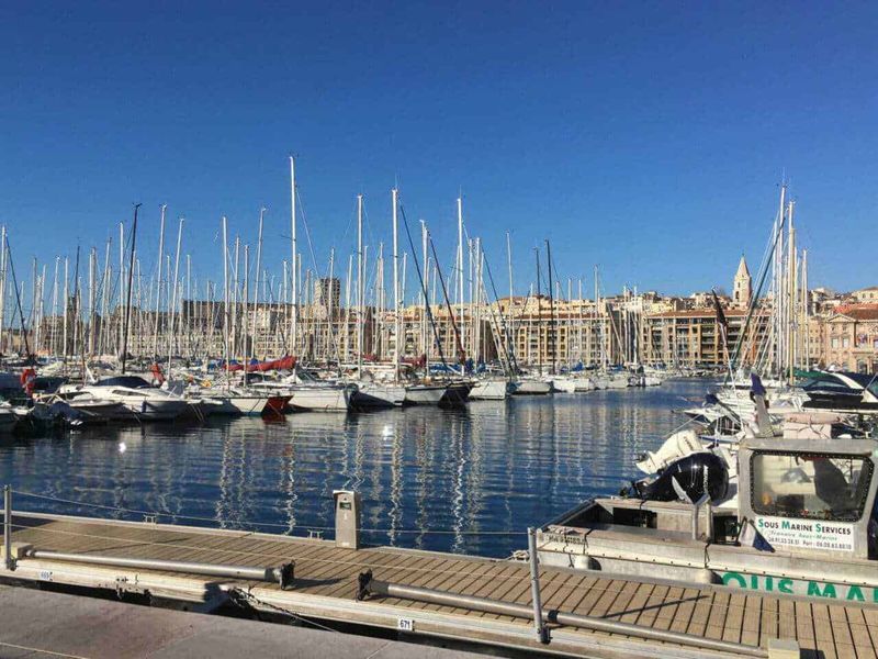 Cosa vedere a Marsiglia a piedi dal porto di sera 2 Marsiglia a piedi di sera: Vela nel porto di Nizza con vista sulla città storica e il mare più blu, perfetta per foto di panorami marittimi e destinazioni mediterranee.