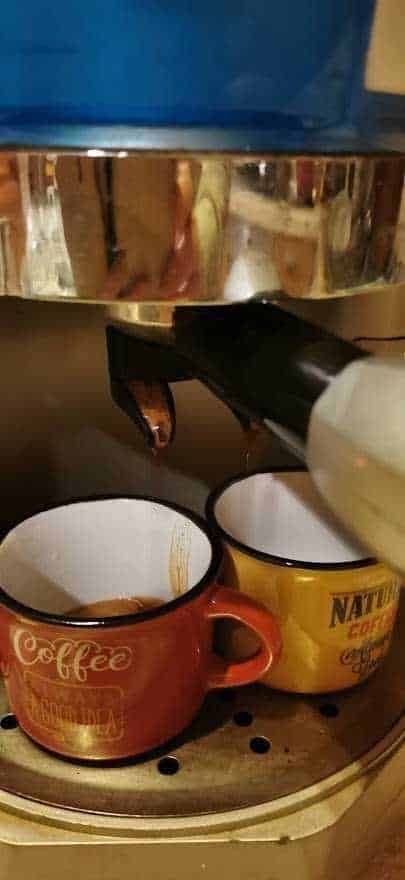 Espresso macchina che prepara caffè in tazze in stile vintage, per appunti sul blog, immagini di cucina e relax, attrezzature da barista, caffetteria artigianale, esperienza culinaria italiana, atmosfera accogliente e calda, produzione di caffè autentico.