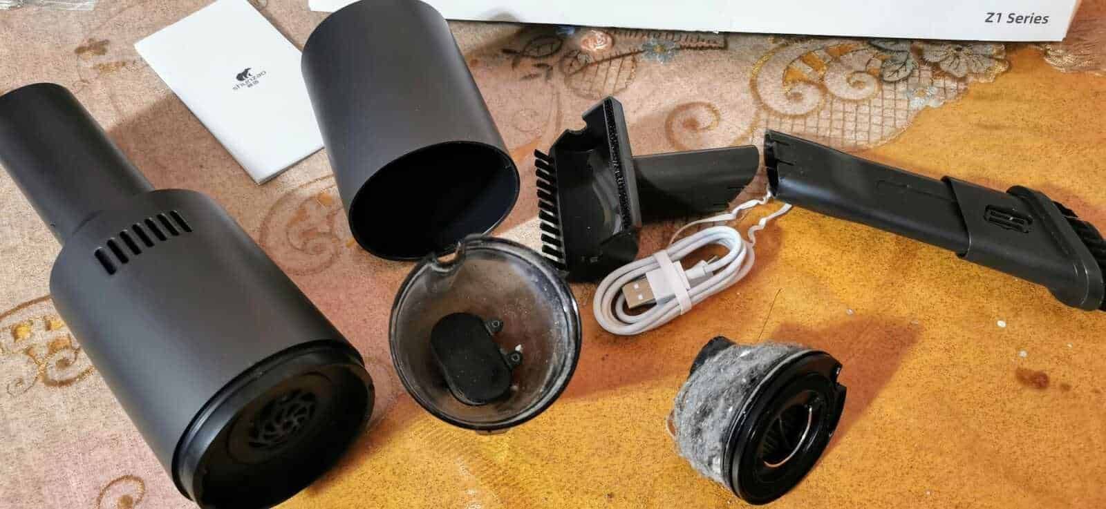 Fili di diversi accessori per aspirazione con motore, tubi e filtri, disposti su una superficie in tessuto color giallo arancione, pronti per essere assemblati o sostituiti.