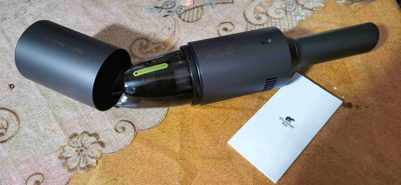Aspirapolvere XIAOMI senza fili per auto SHUNZAO Mijia z1 4 Aspirapolvere senza fili Dyson V15 Detect in colore nero, posizionato su un tavolo di legno chiaro con dettagli decorativi, perfetto per la pulizia moderna ed efficiente della casa.