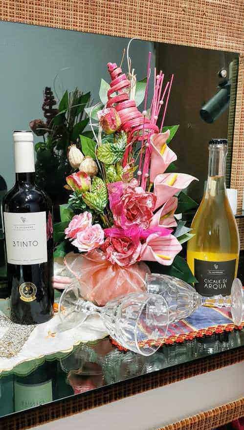 Bouquet di fiori colorati con bottiglie di vino e calici, decorazione elegante per occasioni speciali, allestimento per feste o celebrazioni, dettagli raffinati e atmosfera festosa.